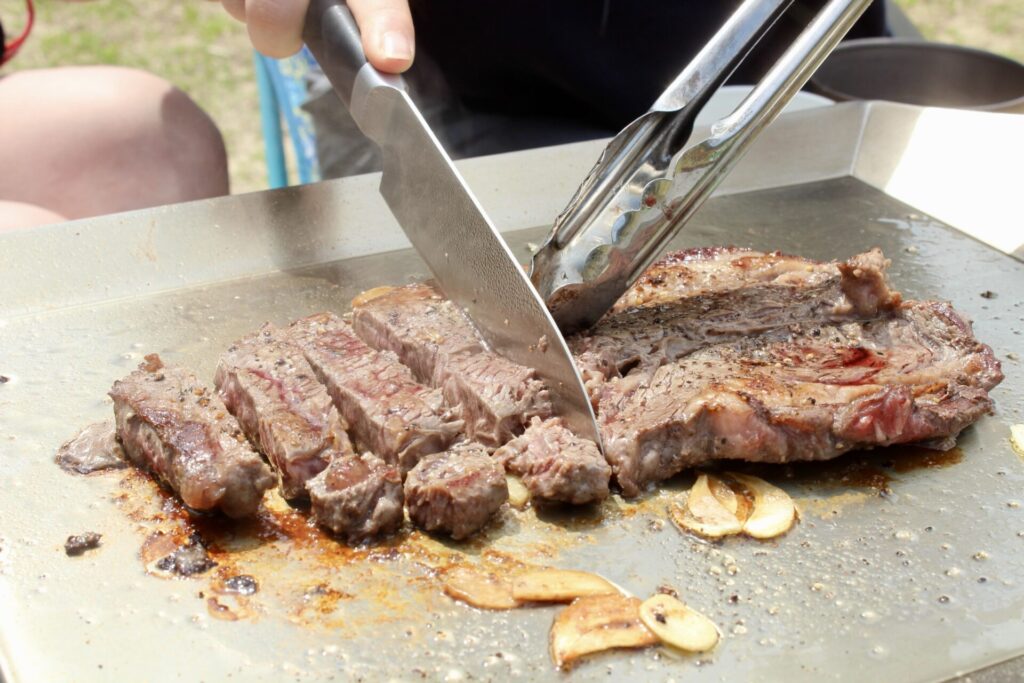イワタニの鉄板『ホームシェフプレート』でステーキ肉を切り分けている様子
